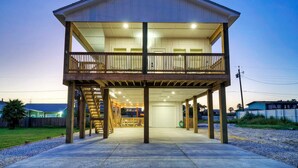 A two-story house with a balcony, a covered porch, and a garage. - New Build! Priv Pool, Firepit, Walk to the Beach | Alright, Alright by AvantStay (Port Aransas)