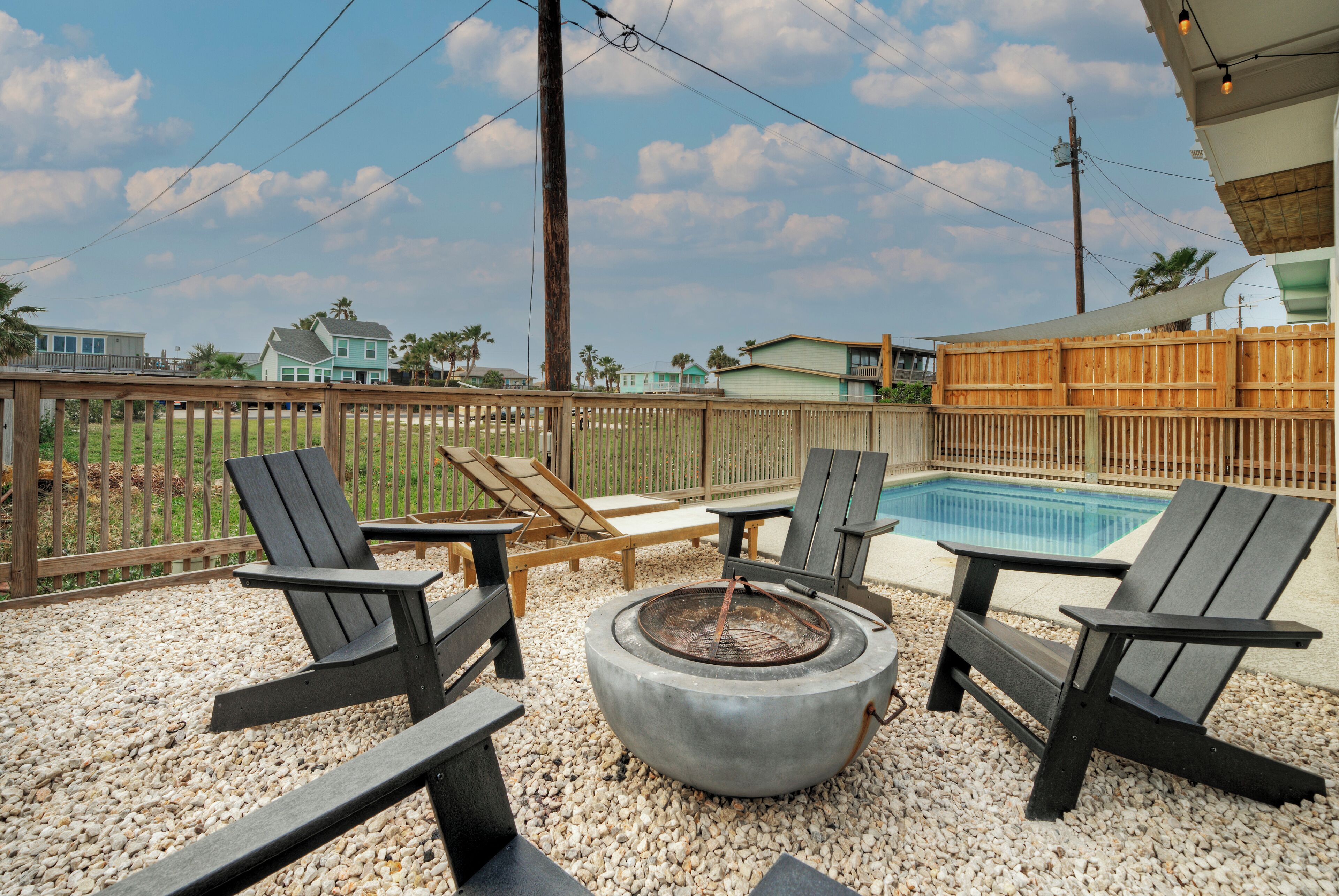 A backyard with a fire pit, outdoor seating, and a swimming pool.