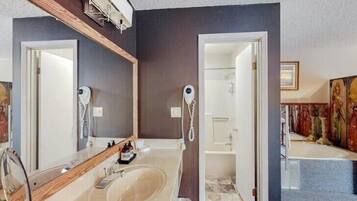 A modern bathroom with a large mirror, a sink, and a shower.