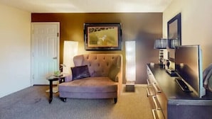 A living room with a sofa, a television, a framed picture, and a lamp. - Suite Dreams 101 at Tradewinds (Eureka Springs)