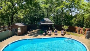 A swimming pool with lounge chairs and a gazebo in a shaded area surrounded by trees. - Suite Dreams 101 at Tradewinds (Eureka Springs)