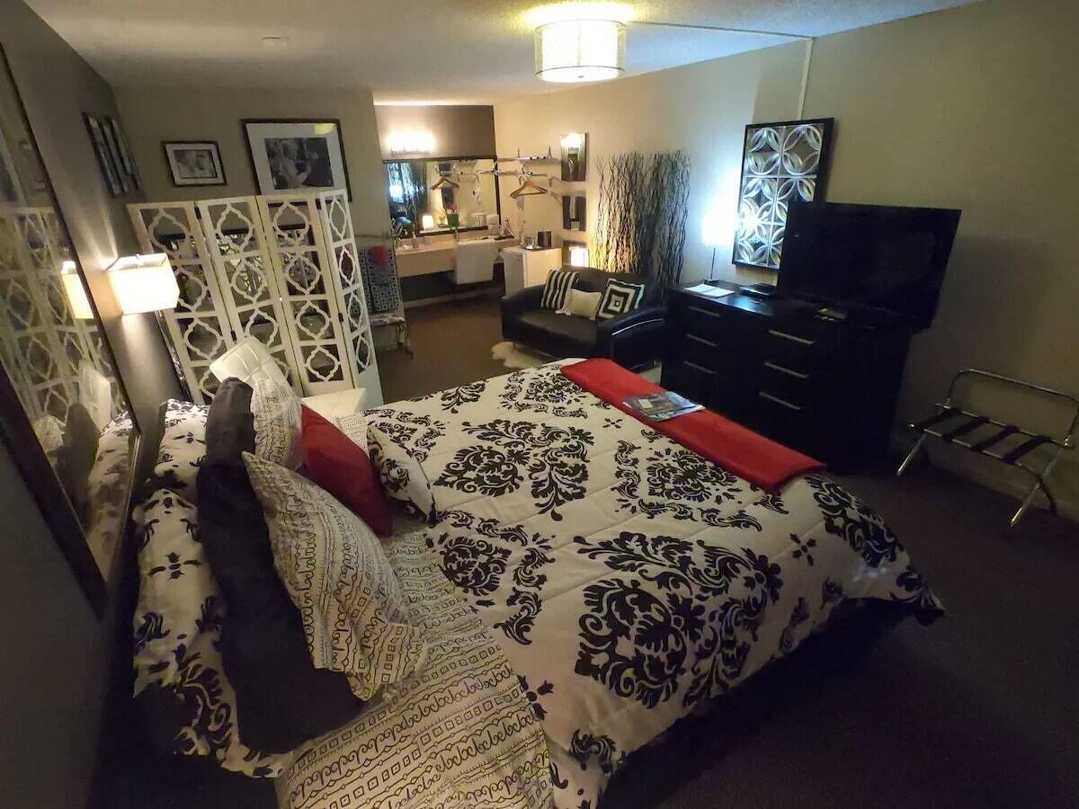 Un dormitorio con una cama, un tocador, un televisor y un escritorio.