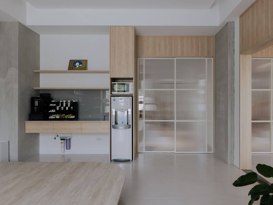 A modern kitchen with wooden cabinets, a built-in microwave, and a water dispenser.