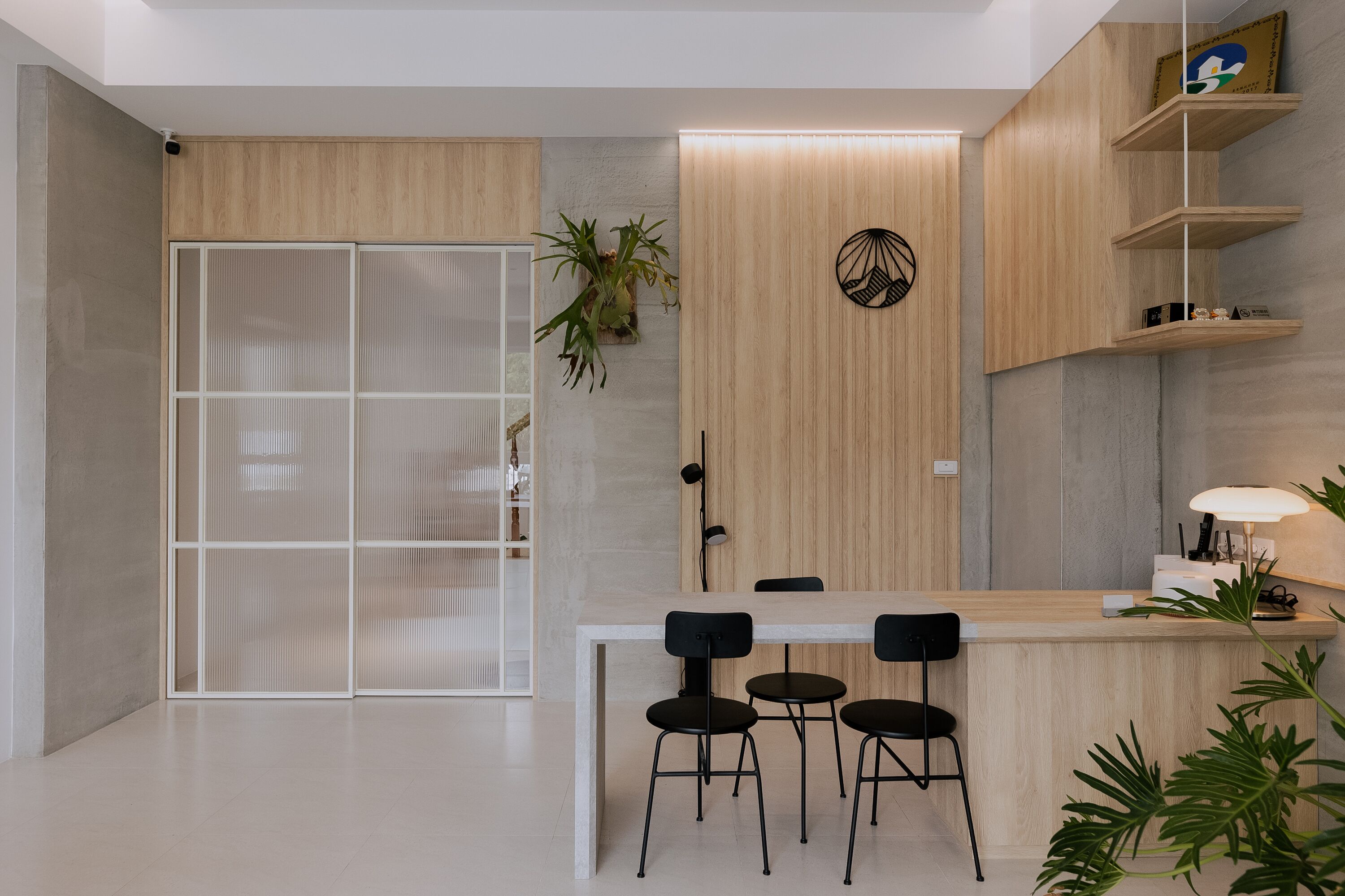 Una cocina moderna con encimera de madera, tres sillas negras y una mesa de comedor blanca.