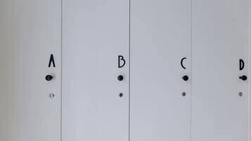 Cuatro taquillas blancas con manijas y tornillos negros, etiquetadas A, B, C y D.