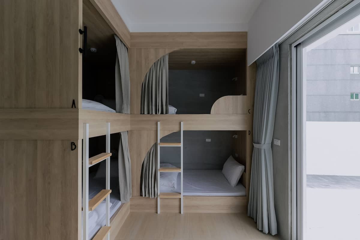 A bunk bed room with wooden walls and a window.