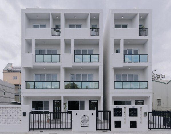 A modern multi-story building with balconies, a gated entrance, and a logo indicating it is a hotel. - terumahouse (Taitung)