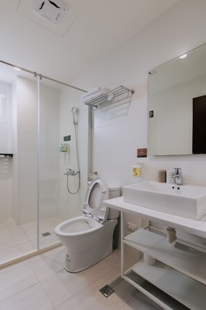 A modern bathroom with a glass-enclosed shower, a toilet, and a sink with a mirror above. - terumahouse (Taitung)