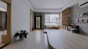 A modern, minimalist living room with a large window, built-in shelving, and a potted plant. - terumahouse (Taitung)