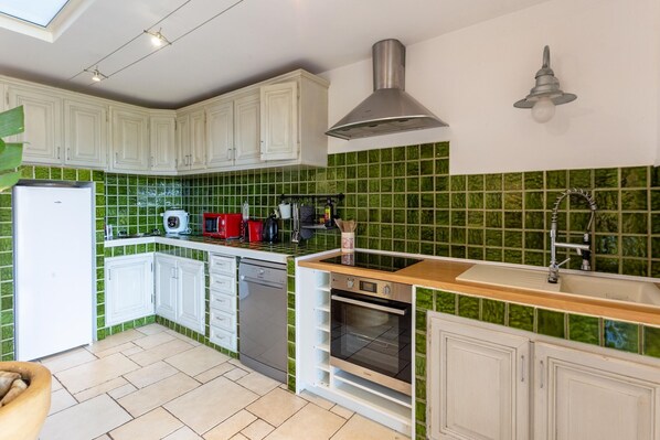 A kitchen with white cabinets, a green tiled backsplash, a built-in oven, and a dishwasher.