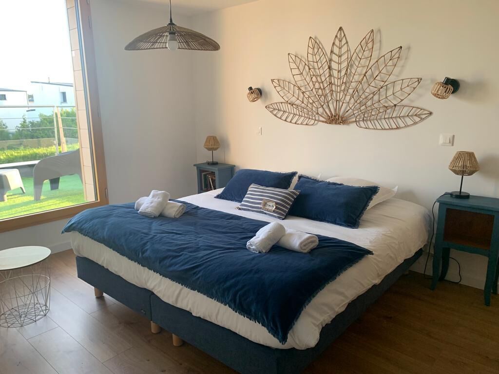 Een slaapkamer met een groot bed, een bladdecoratie aan de muur en uitzicht op de omgeving.