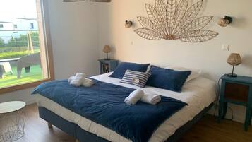 Een slaapkamer met een groot bed, een bladdecoratie aan de muur en uitzicht op de omgeving.