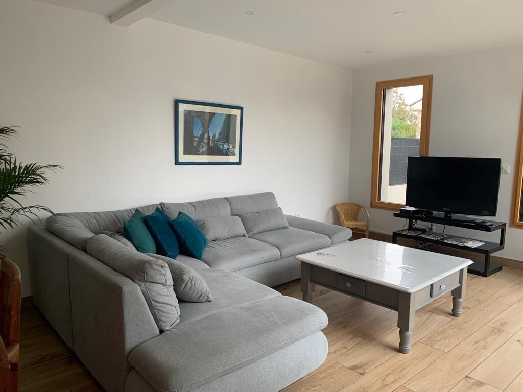 A modern living room with a grey sectional sofa, a white coffee table, a television on a stand, and a framed picture on the wall.
