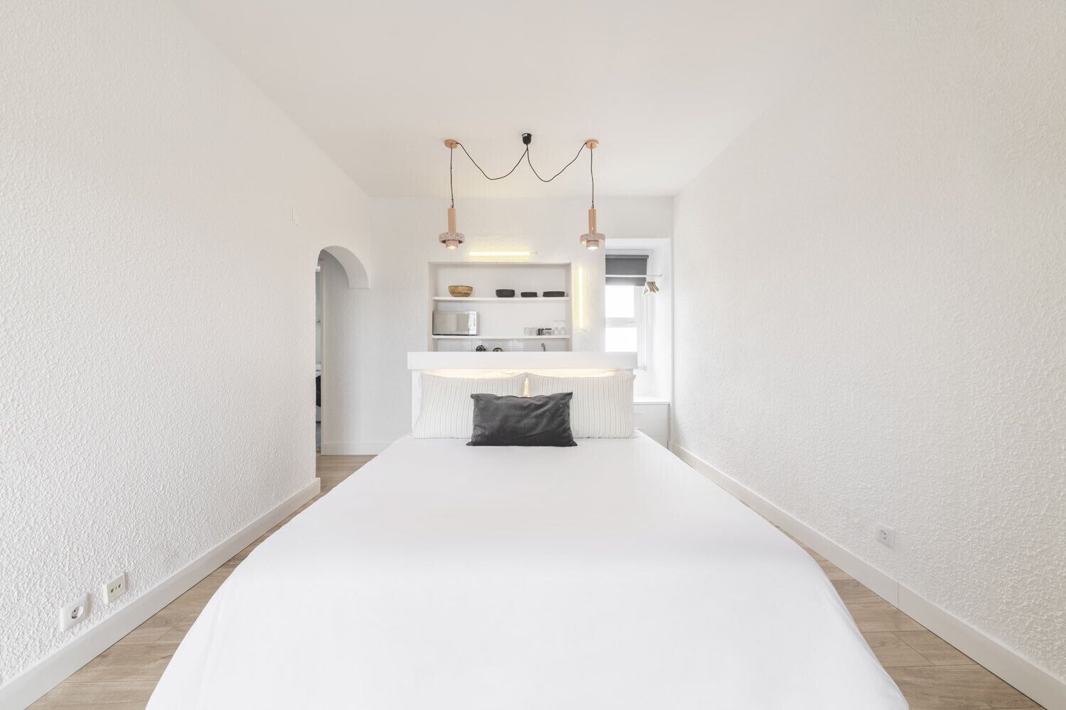 Un dormitorio minimalista con una cama grande, una mesita de noche y un armario empotrado.