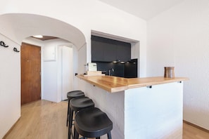 A modern kitchen with a wooden countertop and black stools.