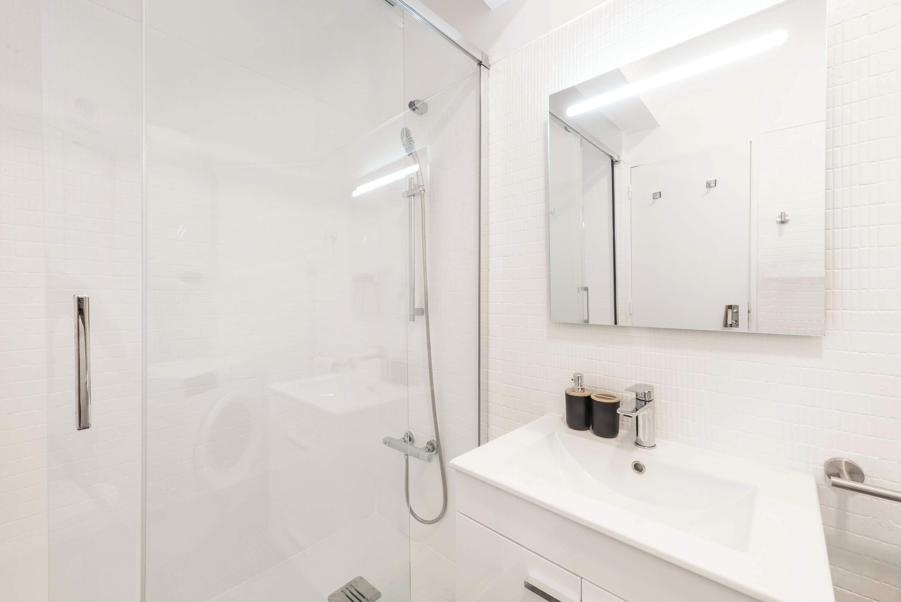 A modern bathroom with a glass-enclosed shower, a white sink, and a mirror above the sink.