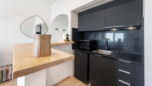 Una cocina moderna con armarios negros, encimera de madera, microondas y fregadero.