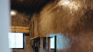 Una habitación con un banco de madera, una repisa en la pared y un ventanal.