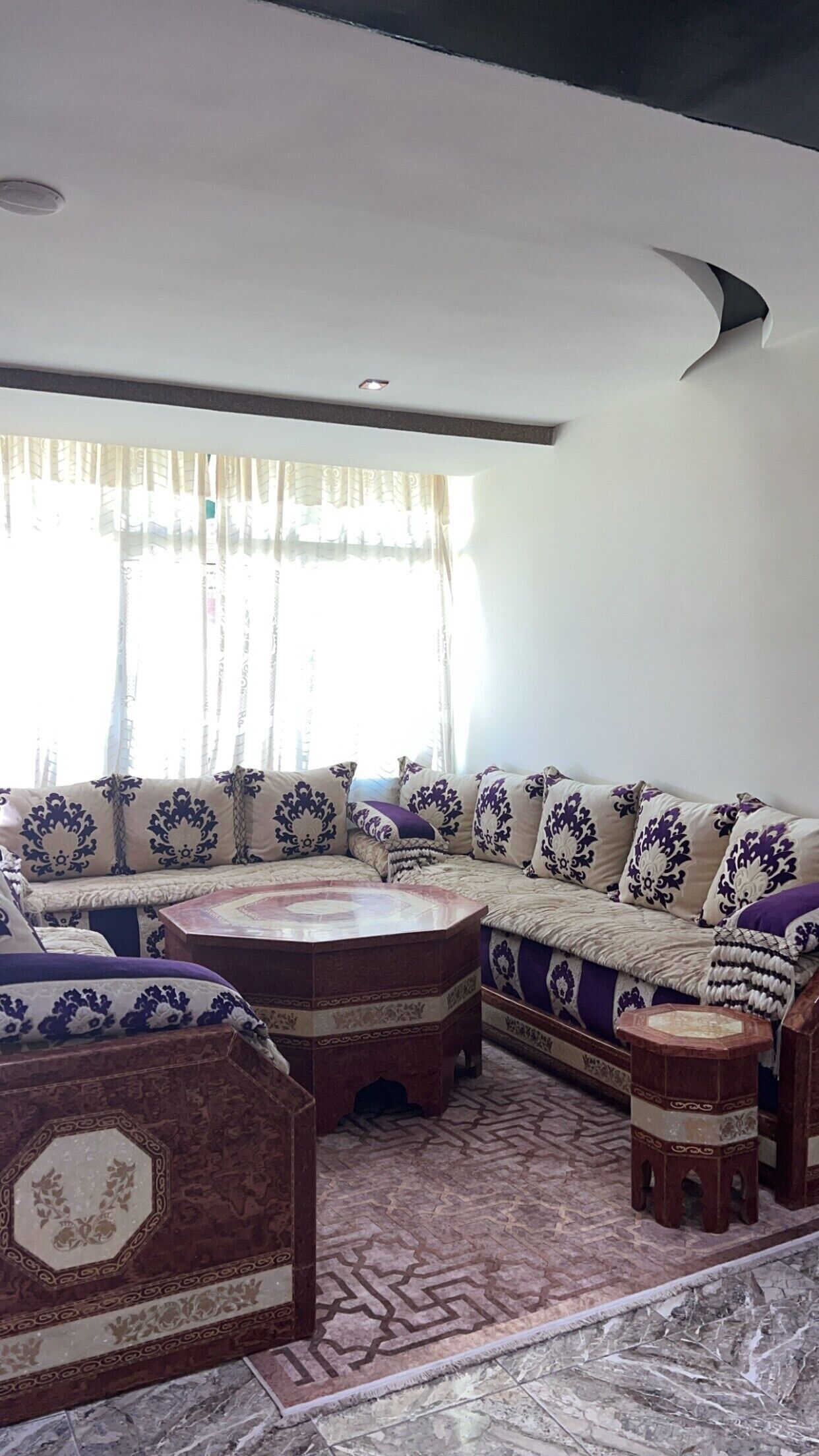A living room with a large L-shaped sofa, a round coffee table, and a small ottoman.