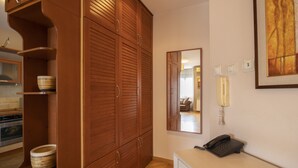 A room with wooden cabinets, a mirror, a phone, and a kitchen area in the background. - Belgrade Center Apartment  Lux II (Belgrade)