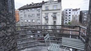 A balcony with a metal railing, a white bench, and a view of multi-story residential buildings. - Belgrade Center Apartment  Lux II (Belgrade)