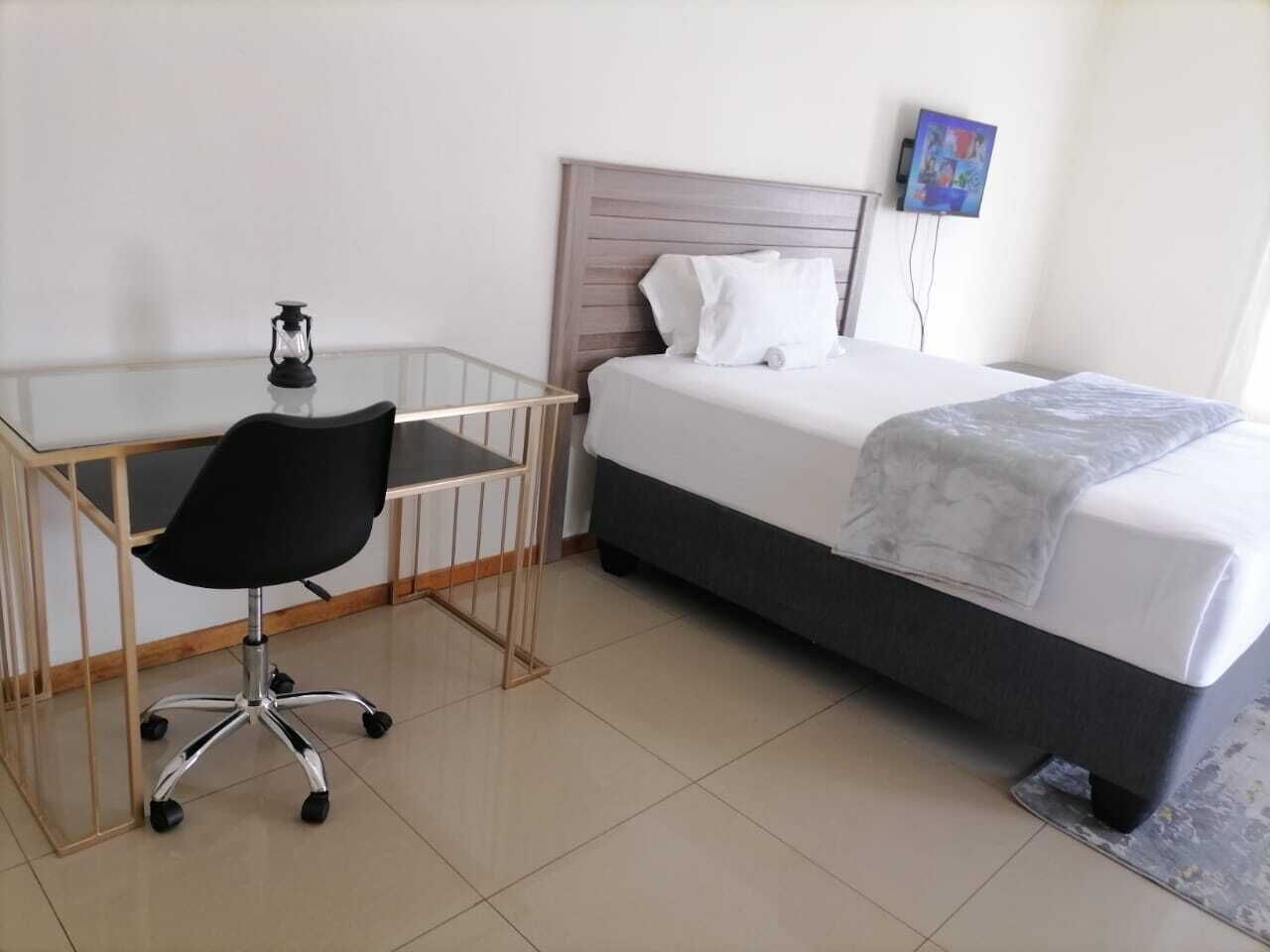 A bedroom with a bed, a desk, and a chair.