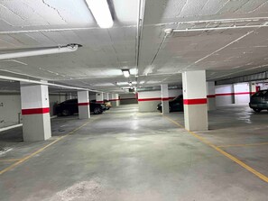 Underground parking with concrete pillars and designated parking spaces.