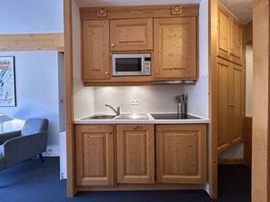 A compact kitchen with wooden cabinets, a microwave, and a sink.
