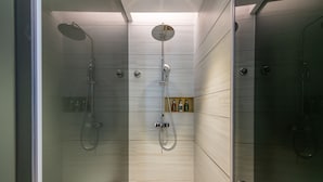 En modern dusch med ett handhållet duschmunstycke och ett väggmonterat takduschmunstycke.