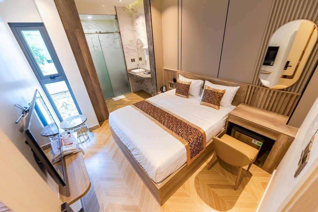 Ein modernes Schlafzimmer mit einem großen Bett, einem Nachttisch aus Holz, einem Spiegel und einem Badezimmer mit Marmorwand und Waschbecken.