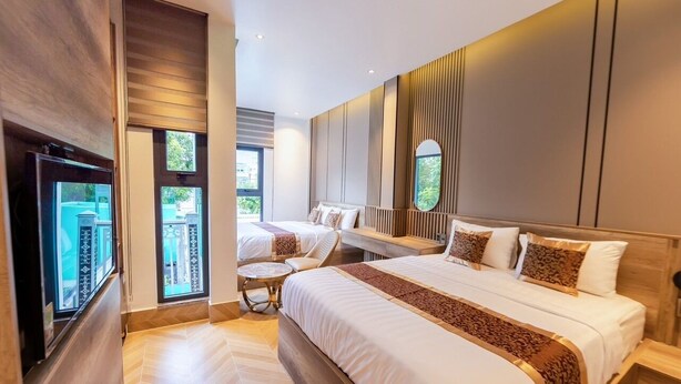 A modern hotel room with a large bed, a seating area, and a TV. - My My Hotel 2 (Ho Chi Minh City)