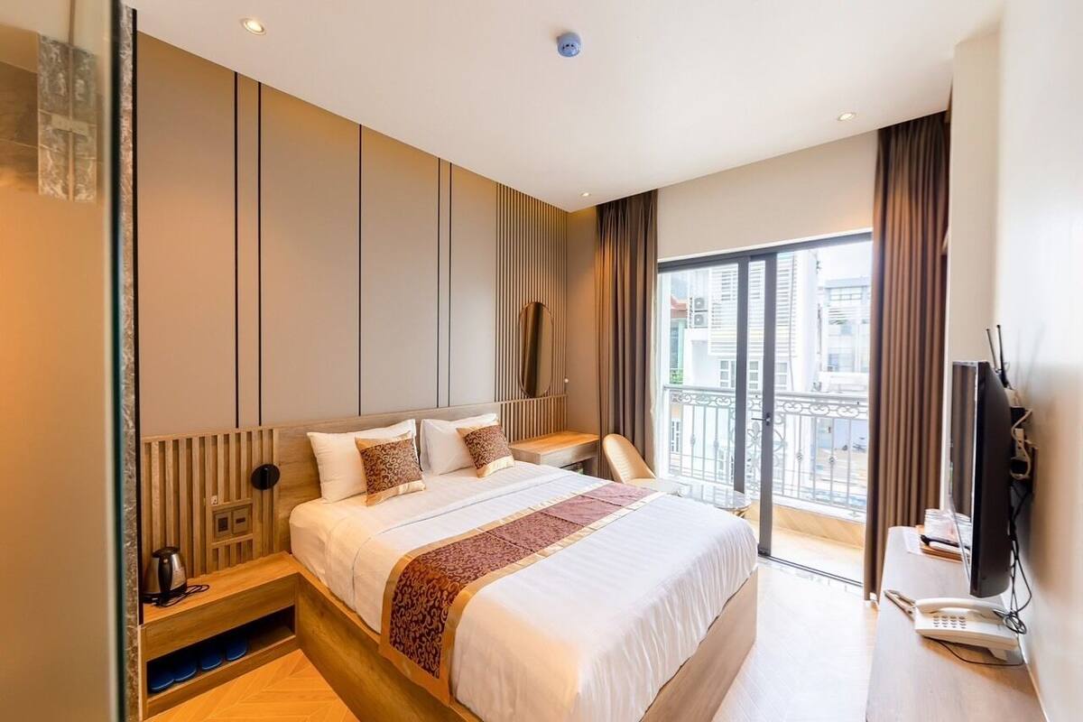 Een moderne hotelkamer met een groot bed, een bureau, een televisie en een balkon met uitzicht over de stad.
