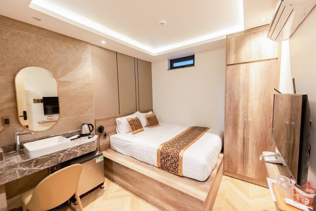Een moderne hotelkamer met een groot bed, een inbouwkantoor, een kaptafel met spiegel en een kledingkast.