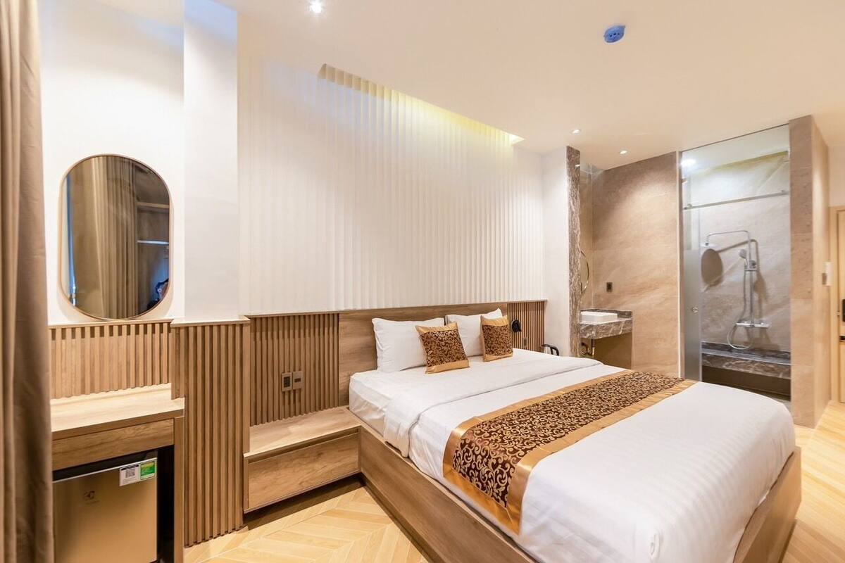 Een moderne hotelkamer met een groot bed, een houten hoofdeinde, een kaptafel met spiegel en een douche.