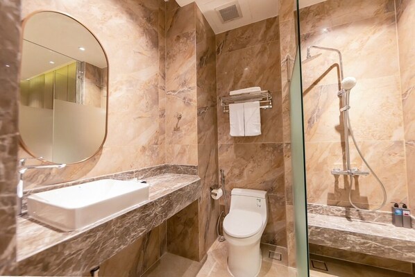 Een moderne badkamer met een marmeren wastafel, toilet en douche.