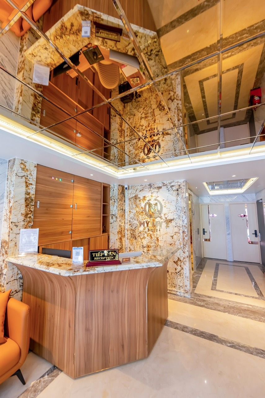 Een hotel receptie met een marmeren balie, houten kasten en een modern design.