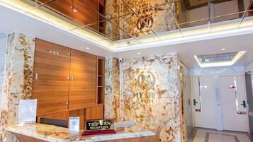 Een hotel receptie met een marmeren balie, houten kasten en een modern design.