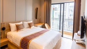 A modern hotel room with a large bed, a wooden headboard, a desk with a telephone, and a balcony with a view of the city. - My My Hotel 2 (Ho Chi Minh City)