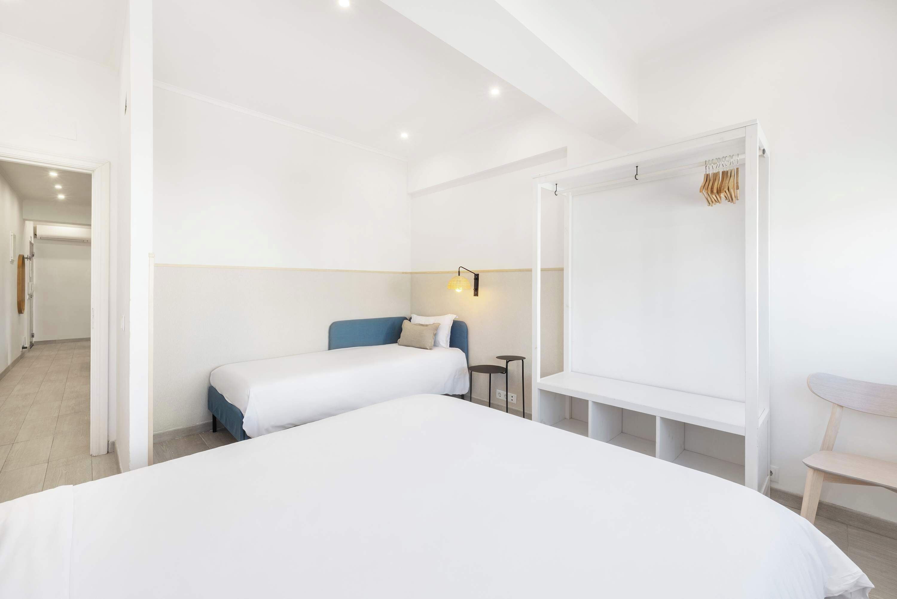 A hotel room with a large bed, a bedside table, a chair, and a wardrobe.