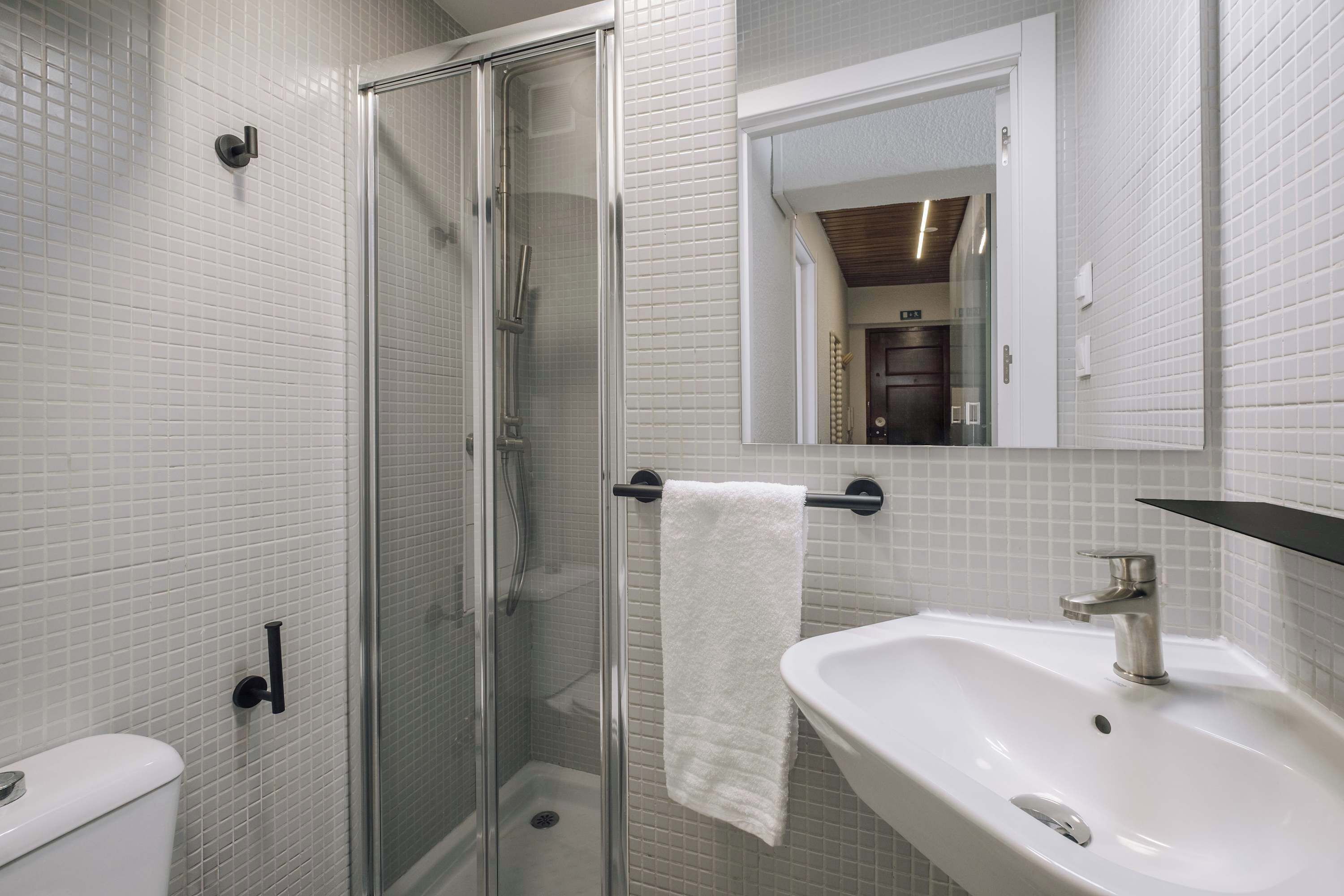 A bathroom with a glass-enclosed shower, a white sink, and a mirror above the sink.