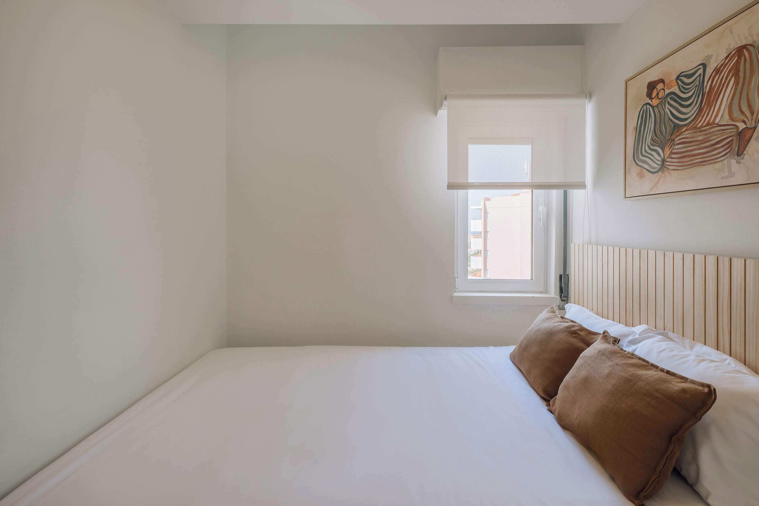 Ein Schlafzimmer mit Bett, Fenster und einem Bild an der Wand.