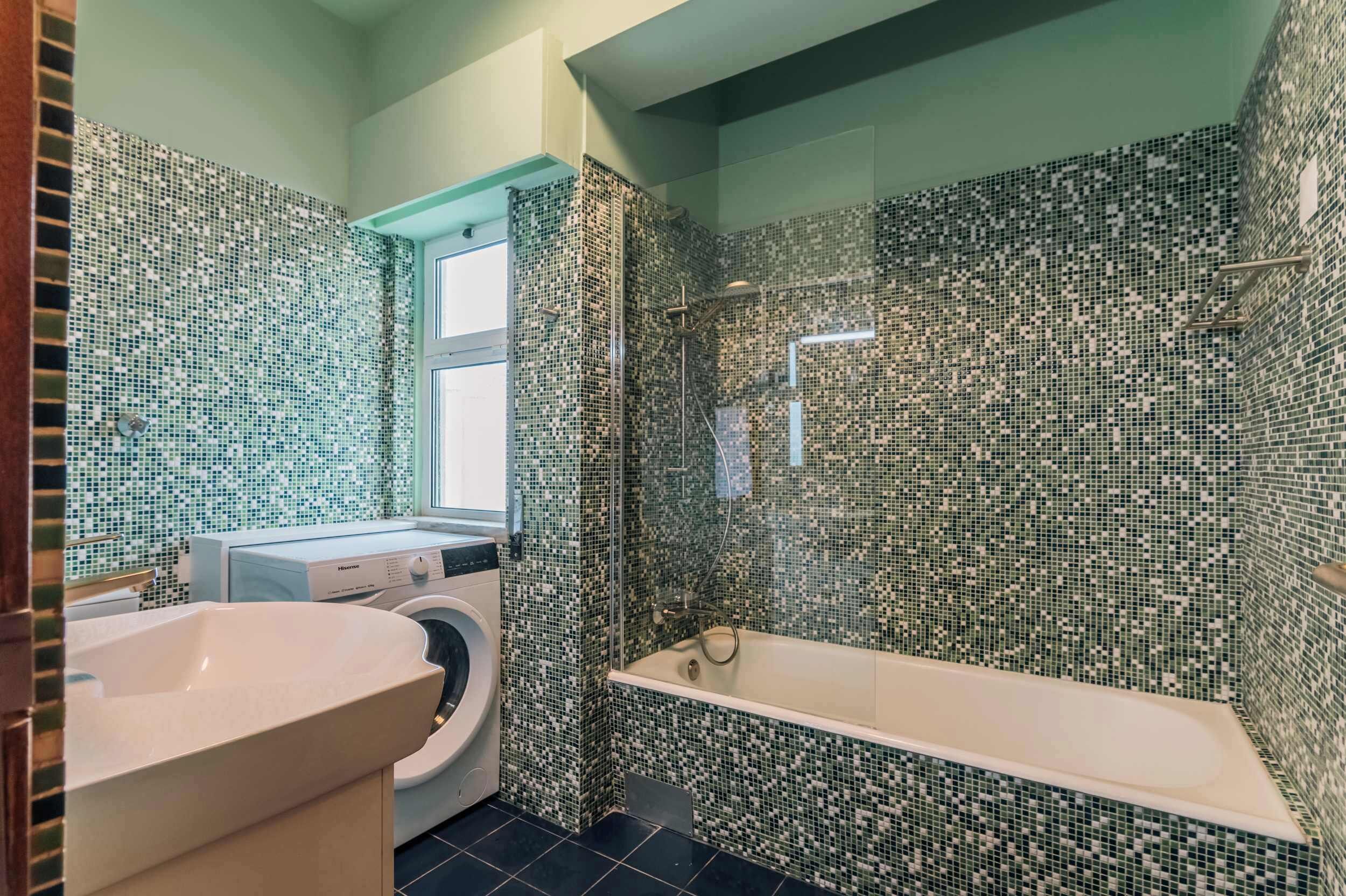 A bathroom with a washing machine, a bathtub, and a sink.