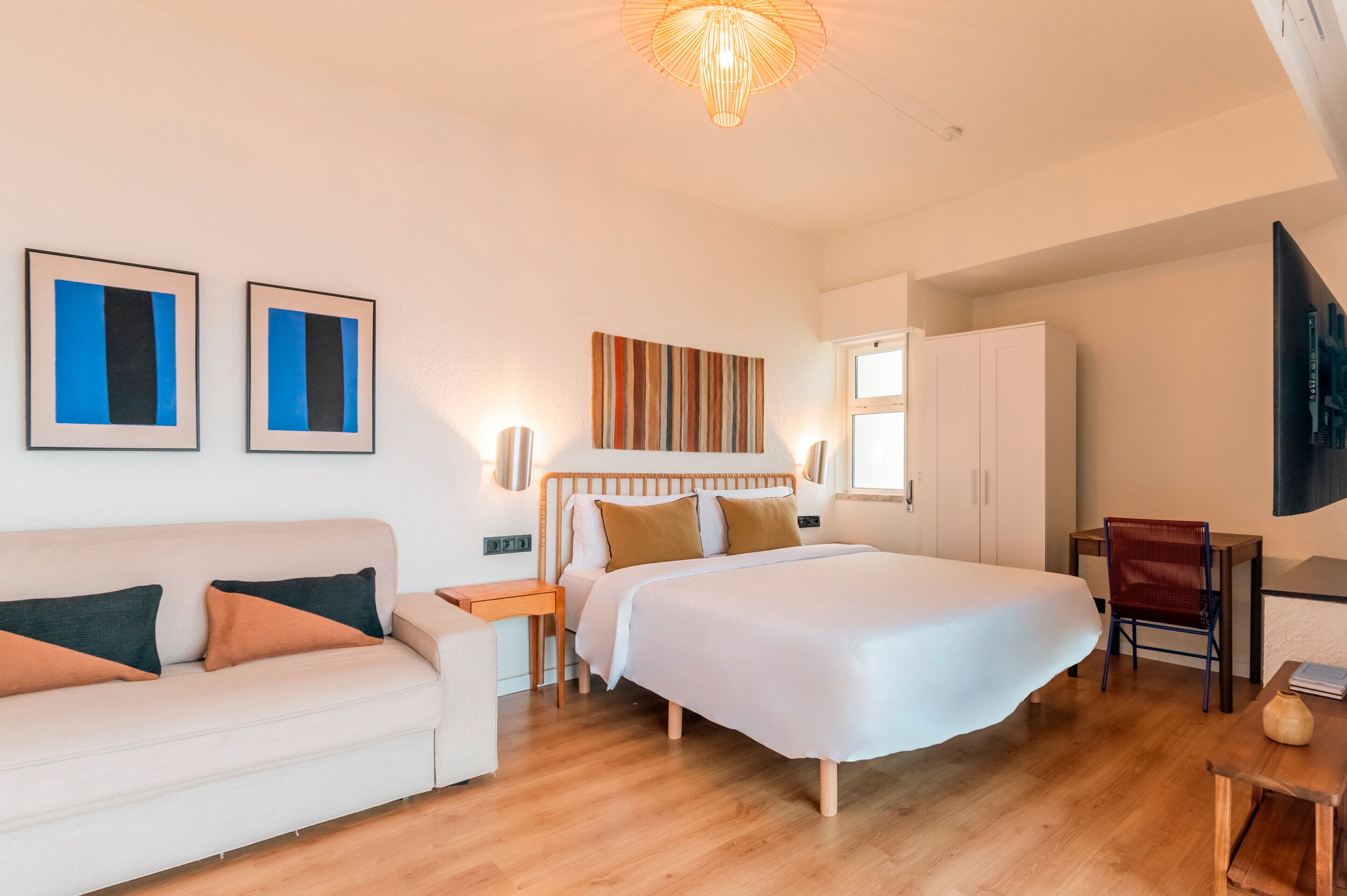 A bedroom with a bed, a sofa, a desk, and a chair.