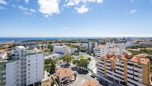 A coastal cityscape with modern buildings, a clear sky, and a view of the sea. - Equador Studios by Olala Homes (Cascais)