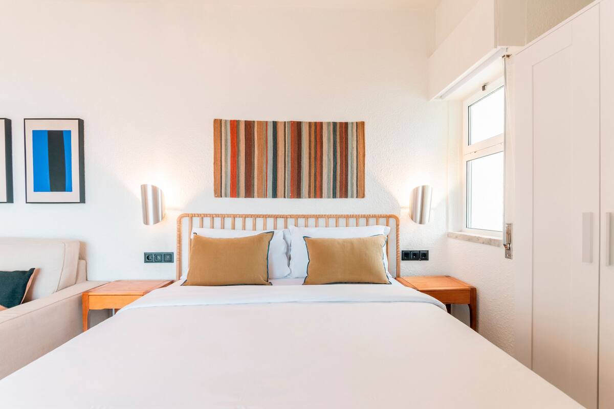 Een hotelkamer met een bed, nachtkastjes, een hoofdeinde, een wanddecoratie en een raam.