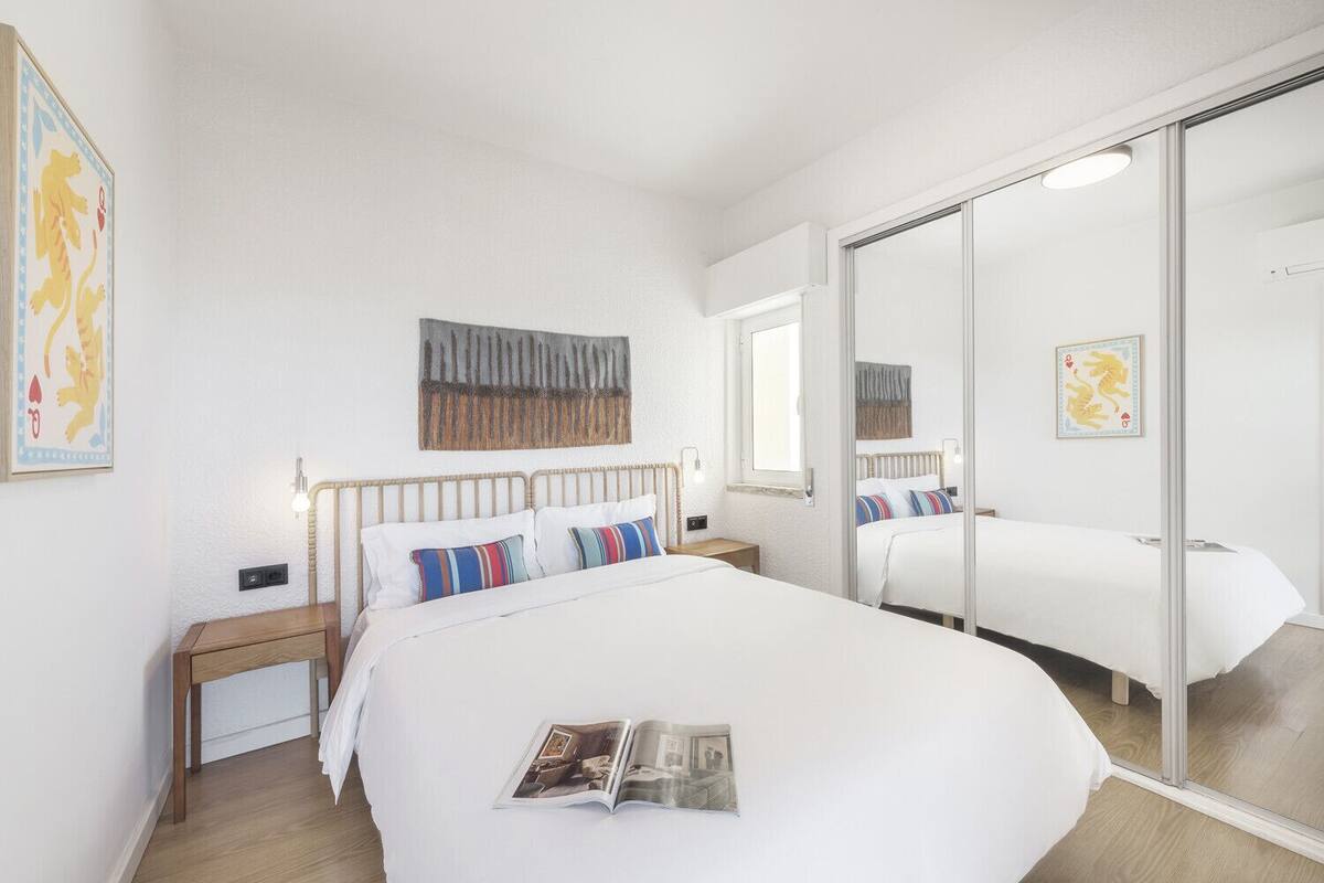 Een hotelkamer met een groot bed, een nachtkastje, een spiegel en kunstwerken aan de muur.