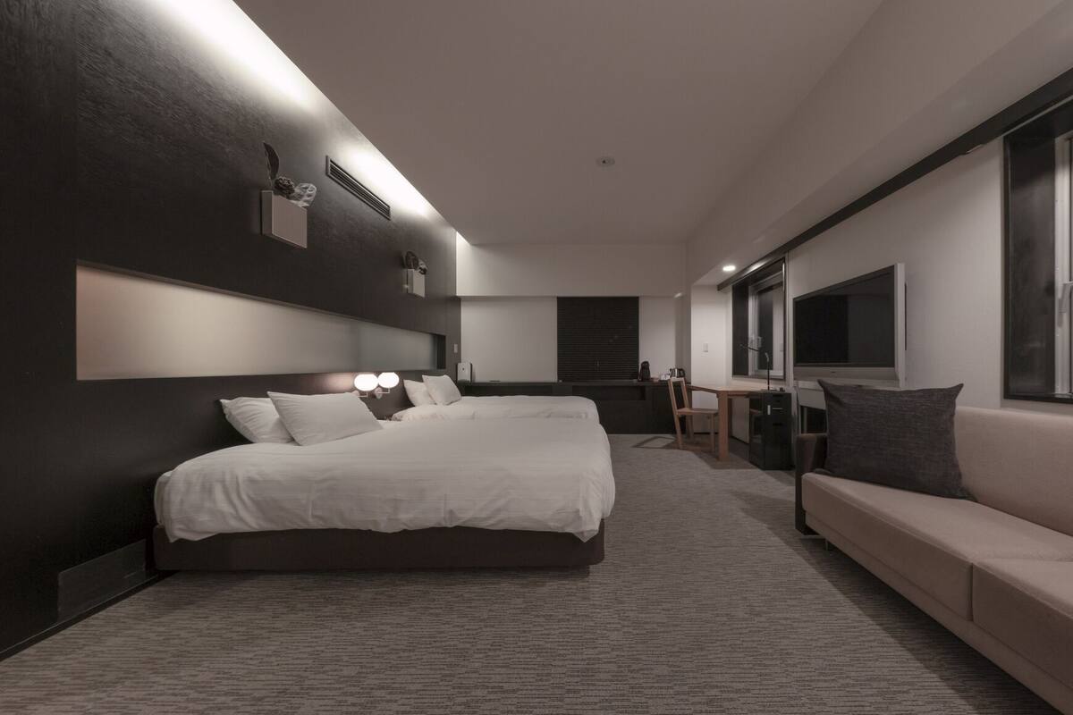 Una habitación de hotel moderna con una cama grande, un escritorio, un sofá y un televisor.