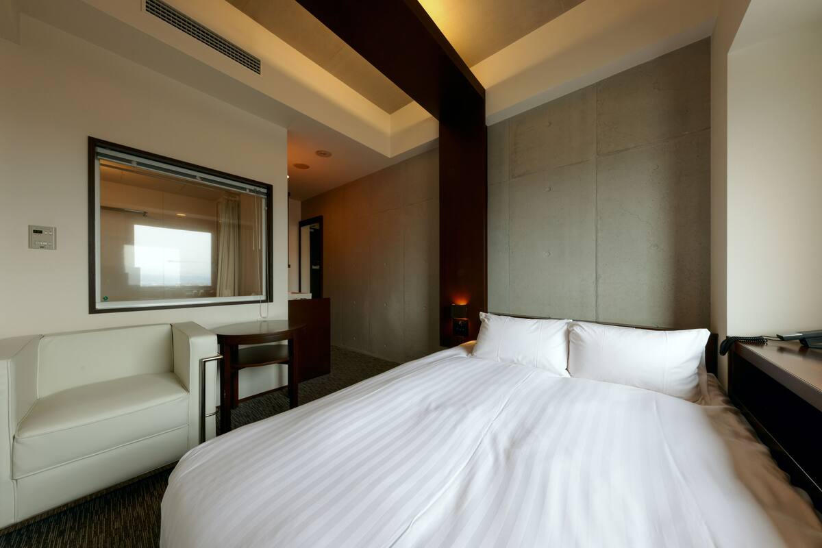 Una habitación de hotel con una cama grande, un sofá, un escritorio y un espejo.