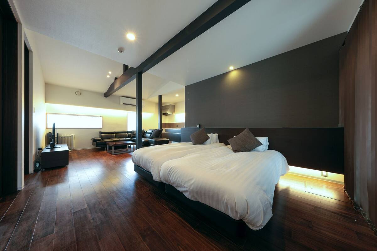 Una habitación de hotel moderna con una cama grande, un sofá, una mesa de centro y un televisor.