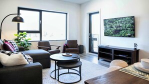 Una sala de estar moderna con sofá, sillones, una mesa de centro, televisor y un amplio ventanal.